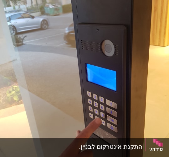 אדם לוחץ על מקשי אינטרקום עם מסך כחול